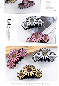 Détail de pinces à cheveux fleuries avec marguerites roses blanches et jaunes sur noir