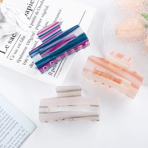 Three striped acetate hair claws in blue, pink, and grey with a pearlescent finish