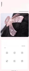 Close-up of pink butterfly wing hair claw clip with floral marble texture on dark hair