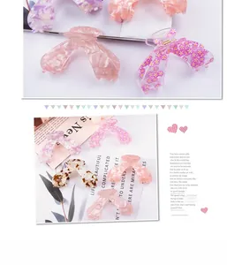 Close-up of butterfly wing hair claws with pink floral and marble acetate patterns