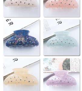 Detail of colorful acrylic hair claws with marble texture and sparkling rhinestones