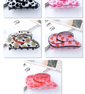 Detail view of various cowboy hat hair claws with cow print and sunflower patterns
