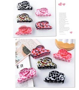 Detail view of five cowboy hat hair clips with cow print and sunflower patterns