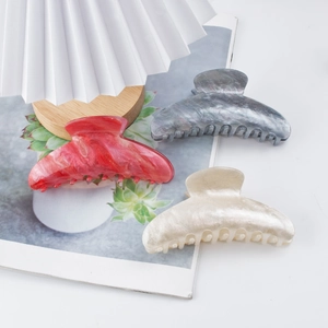 Three large marble pattern acrylic shark hair clips in red, blue, and cream colors