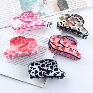 Cowboy hat hair claws with sunflower and cow prints on a magazine background