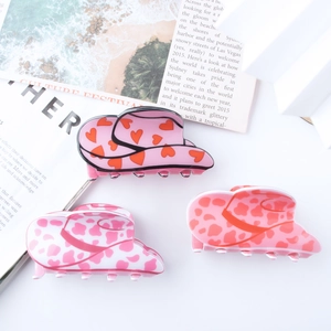 Three cow print and heart pattern cowboy hat shaped hair claws in pink and white