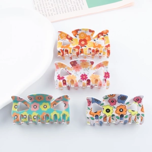 Lot de quatre pinces à cheveux fleuries en orange, rose, vert et bleu sur fond blanc
