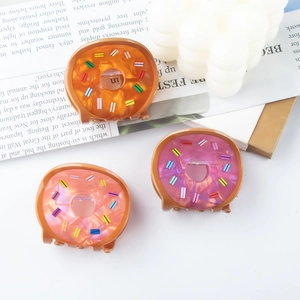 Three colorful doughnut hair clips with pearl texture and sprinkles on vintage paper