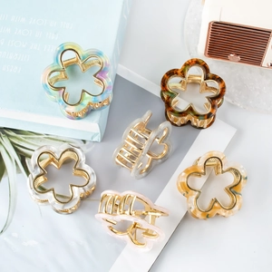 Floral resin and metal hair claws in various colors arranged on a styled desktop