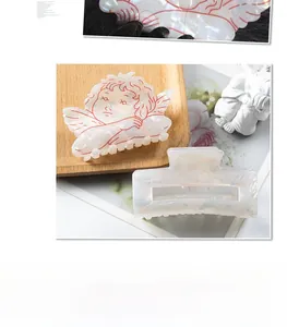 Detailed view of iridescent rectangle hair claw and angel shaped clip in a gift set