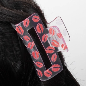 Pinza per capelli quadrata rosa traslucida con motivi a labbra rosse su capelli scuri