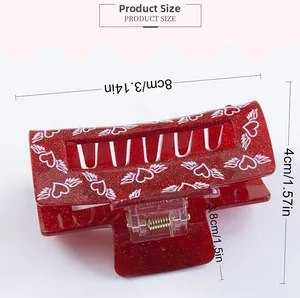 Detail view of 8cm red glitter acrylic hair claw clip with winged heart pattern