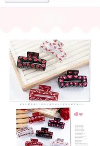 Detail view of assorted heart and lip pattern acrylic hair claws on a wood tray