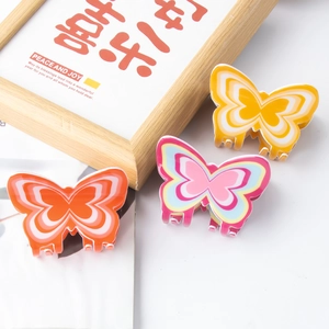 Three colorful 8cm butterfly hair claws in orange, pink, and yellow on a white surface
