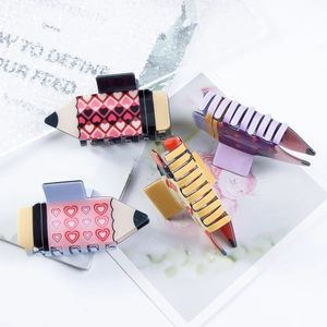 Set of four pencil-shaped hair claws with heart patterns in pink, purple, and yellow