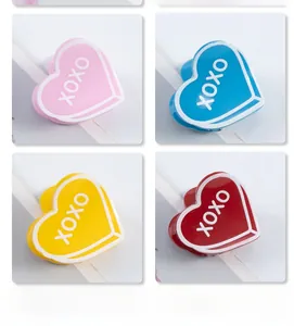 Détail de pinces à cheveux XOXO en forme de cœur aux couleurs acidulées rose, bleu et jaune