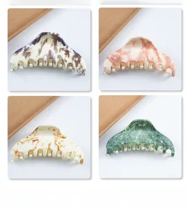 Detail view of four marble texture hair claws in purple, pink, orange, and green patterns