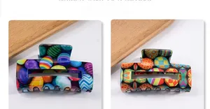 Detail view of two rectangular hair claws with vibrant colorful egg patterns on wood tray