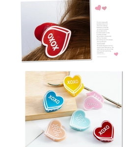 Détail de pinces à cheveux coeur XOXO colorées avec slogans rétro sur fini acrylique