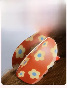 Close-up of orange floral Easter claw clip worn on brown hair with vintage flower design
