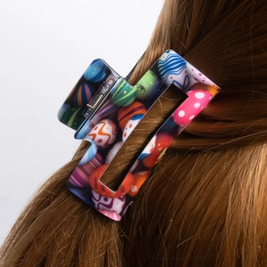 Rectangular shark hair claw clip with colorful Easter egg patterns on brown hair