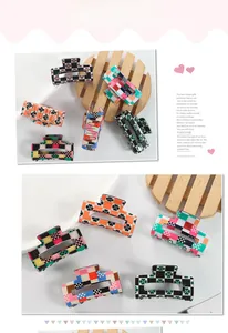 Detail of checkered hair claws in vibrant orange and green colors with floral patterns