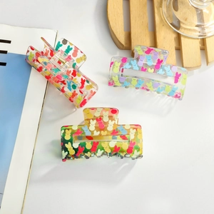 Three acrylic hair claws with colorful cartoon rabbit prints on a clean white surface
