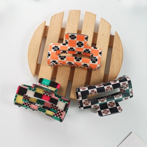 Retro checkered and geometric pattern hair claw clips set on a wooden tray