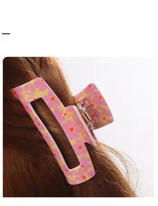 Detail of pink floral hair claw clip with metal spring on brunette wavy hair