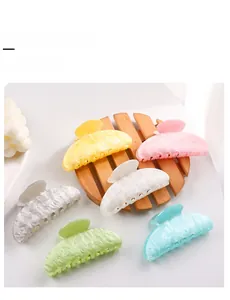 Macro view of six macaron-colored marble texture hair claw clips on a wooden tray