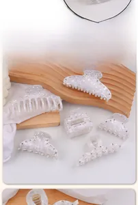 Vue détaillée de pinces à cheveux à motif marbré avec strass sur présentoir en bois