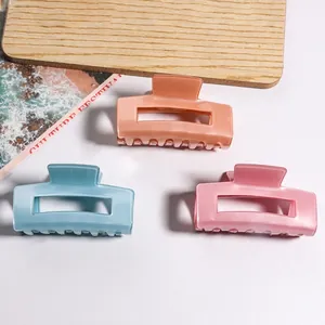 Trois pinces à cheveux carrées minimalistes en bleu, rose et orange sur plateau bois