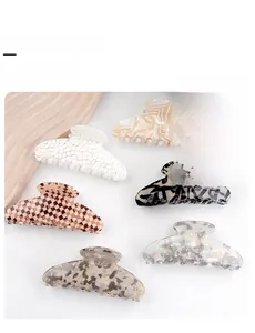Detail showing six acetate hair claw clips with checkerboard and marble textures on a tray
