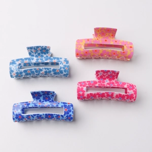 Floral print hair claws in four colors including blue, yellow and pink on grey background