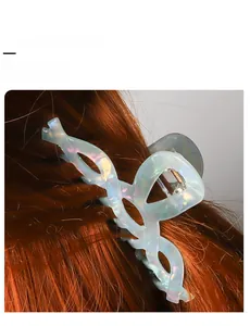 Dettaglio di una molletta per capelli blu cangiante su lunghi capelli castano rossi