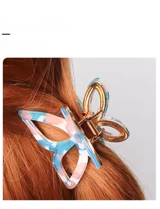 Detailed view of a butterfly hair claw clip with gold frame on a braided hair strand