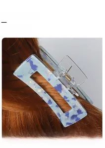 Detail of blue acetate marble hair claw clip with gold spring shown on dark hair
