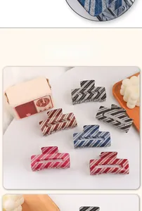Close-up of six glitter-striped rectangular hair claws in various colors on a desk