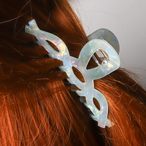 Molla per capelli ondulata azzurro iridescente che tiene i capelli su grigio