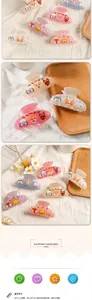Close-up of cute cartoon resin hair claws featuring cats and dogs on a white linen surface