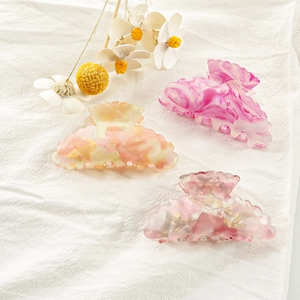 Tre grandi mollette per capelli con motivi marmorizzati rosa e arancione su panno bianco