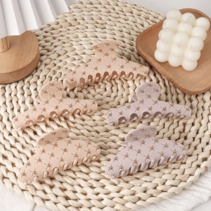 Five matte acrylic shark hair clips with quilted texture and gold studs on straw mat