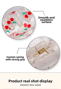 Detail of clear acrylic hair claw clip showing red cherry pattern and sturdy metal spring