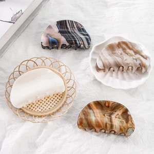 Semi-circular acetate hair claw clips in four elegant patterns on a rustic fabric background