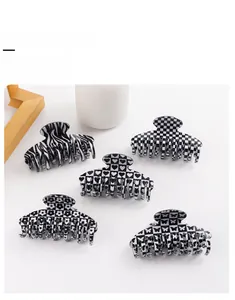 Detailed macro view of black and white patterned hair claw clips with checkered heart and floral designs
