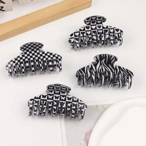 Set of four black and white hair claws featuring heart grid and butterfly patterns