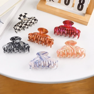 Set of six stylish hair claws in marble and checkered patterns on a white table