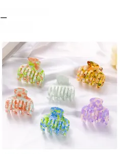 Detailed macro view of 6 colorful mosaic dye hair claw clips on white satin fabric