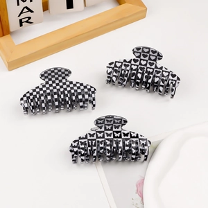 Three pieces of black and white checkerboard hair claws with heart and butterfly designs