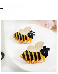 Détail de pinces à cheveux abeille à rayures jaunes noires et ailes blanc nacré